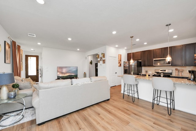 living room featuring recessed lighting, visible vents, and light wood finished floors