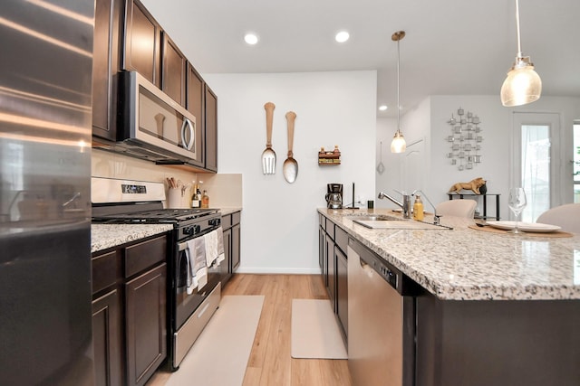 kitchen with dark brown cabinets, a peninsula, stainless steel appliances, and a sink