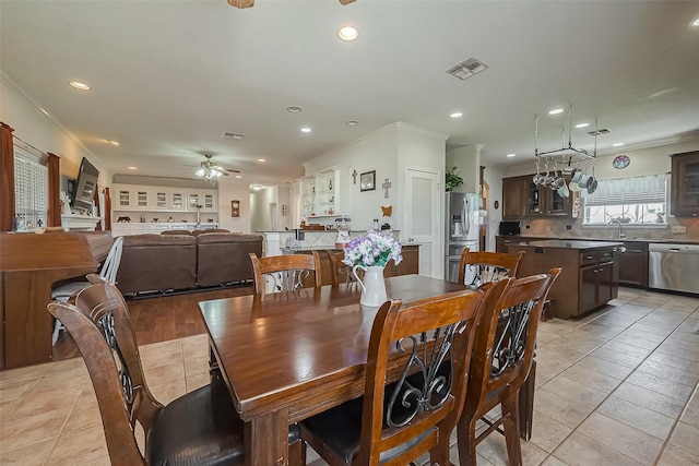 dining space featuring light tile patterned floors, visible vents, a ceiling fan, and crown molding