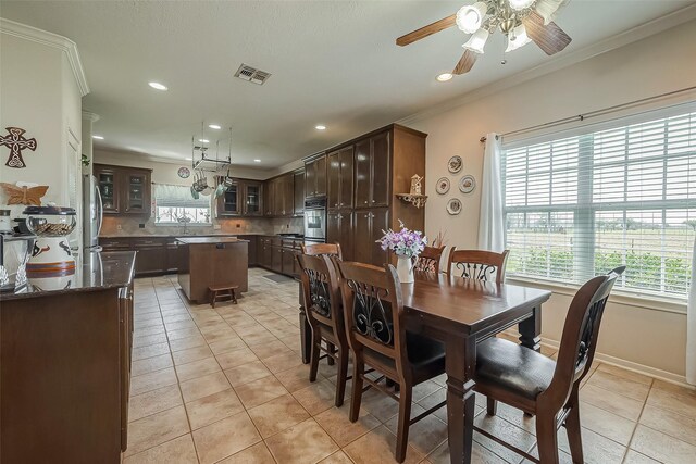 dining space featuring light tile patterned floors, baseboards, visible vents, ceiling fan, and crown molding