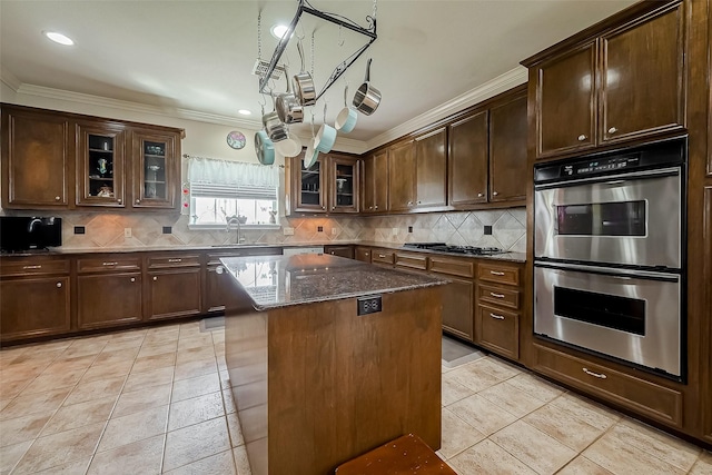 kitchen with ornamental molding, light tile patterned floors, decorative backsplash, appliances with stainless steel finishes, and a sink