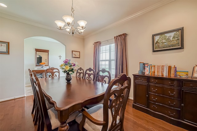 dining area featuring arched walkways, a notable chandelier, wood finished floors, and ornamental molding