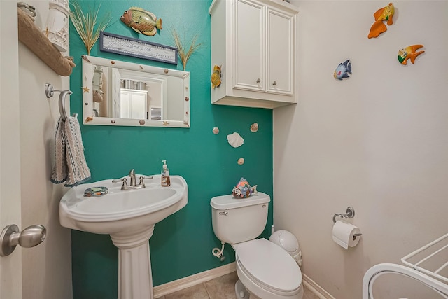 bathroom with tile patterned floors, baseboards, toilet, and a sink