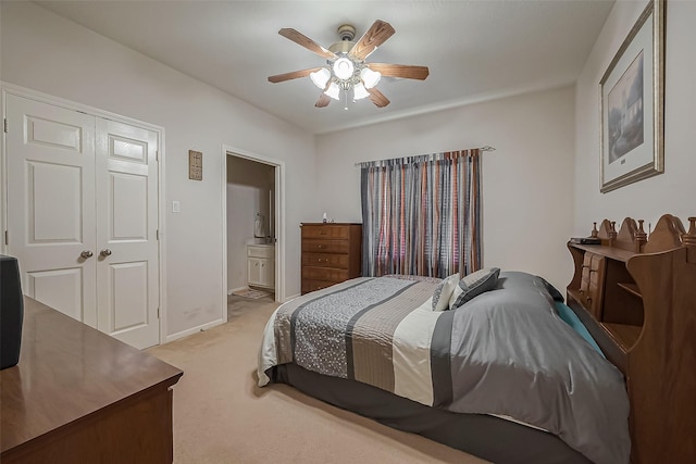 bedroom with light carpet, baseboards, ensuite bath, and ceiling fan