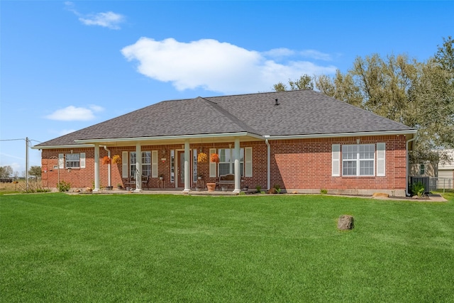 back of house featuring a yard, brick siding, and roof with shingles