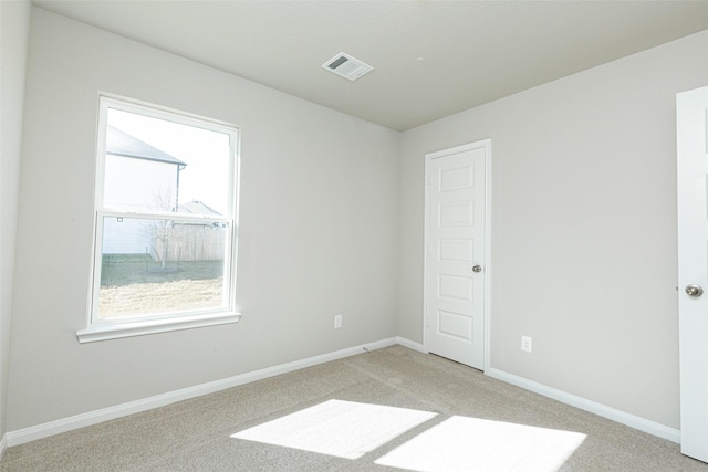 empty room featuring light colored carpet, visible vents, and baseboards