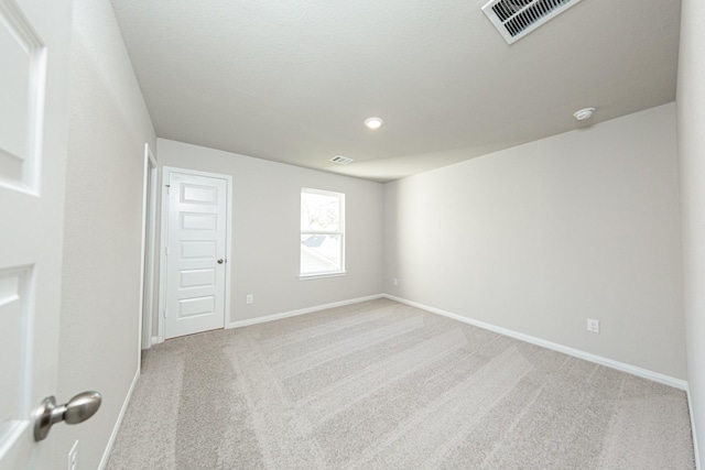 carpeted spare room with visible vents and baseboards