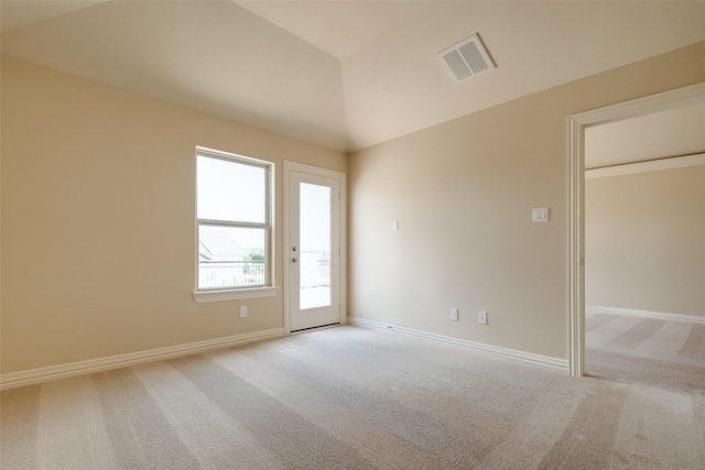 empty room with light carpet, visible vents, baseboards, and vaulted ceiling