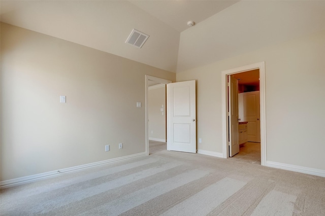 unfurnished bedroom featuring visible vents, light colored carpet, baseboards, and vaulted ceiling