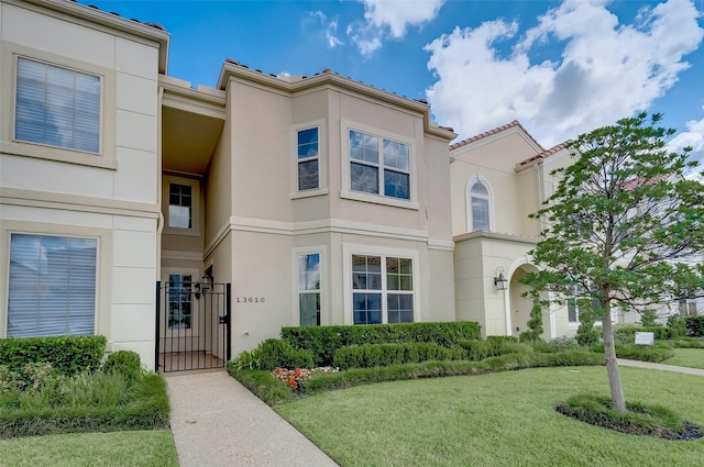 view of front facade with stucco siding, a front lawn, and a gate