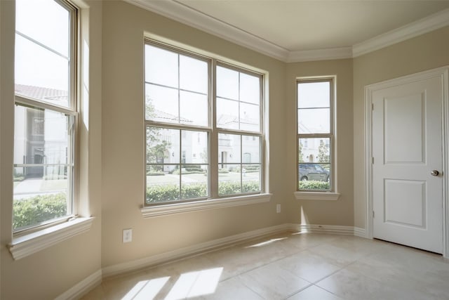 spare room with light tile patterned floors, plenty of natural light, baseboards, and ornamental molding