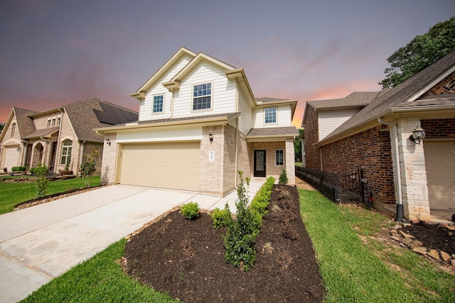 traditional-style house featuring a yard, brick siding, fence, a garage, and concrete driveway
