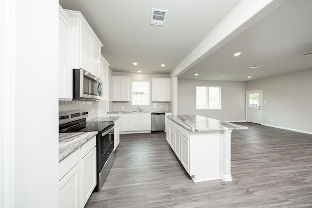 kitchen featuring a center island, visible vents, baseboards, appliances with stainless steel finishes, and decorative backsplash
