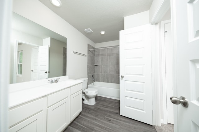 full bath featuring toilet, wood finished floors, vanity, visible vents, and bathtub / shower combination