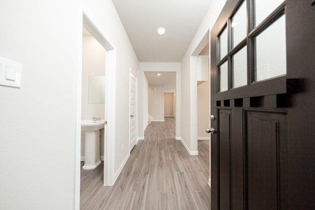hallway with light wood-type flooring, baseboards, and recessed lighting