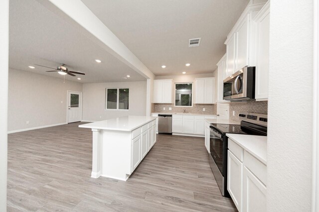 kitchen with stainless steel appliances, recessed lighting, a kitchen island, tasteful backsplash, and light countertops