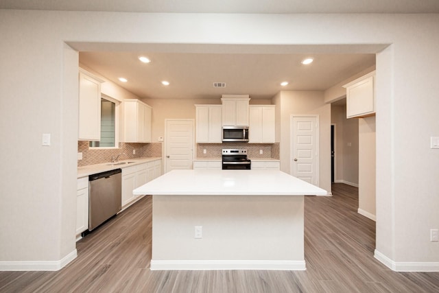 kitchen with stainless steel appliances, a sink, baseboards, tasteful backsplash, and recessed lighting