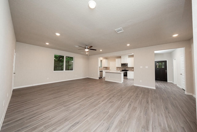 unfurnished living room featuring a ceiling fan, baseboards, wood finished floors, and recessed lighting