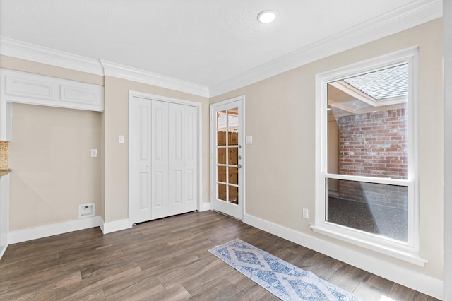 interior space with a closet, baseboards, wood finished floors, and crown molding