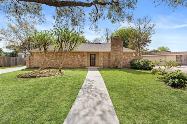 view of front of home featuring brick siding, a shingled roof, a front lawn, fence, and a chimney