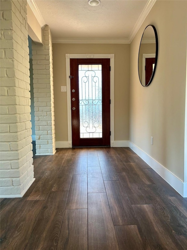 foyer entrance featuring a textured ceiling, ornamental molding, baseboards, and dark wood-style flooring