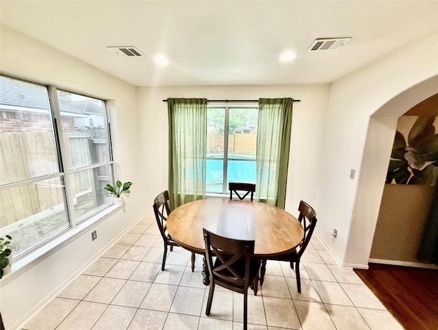 dining space with arched walkways, light tile patterned flooring, and visible vents
