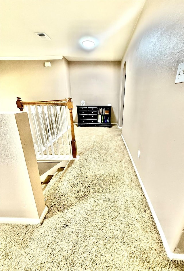 hallway featuring arched walkways, carpet flooring, and baseboards