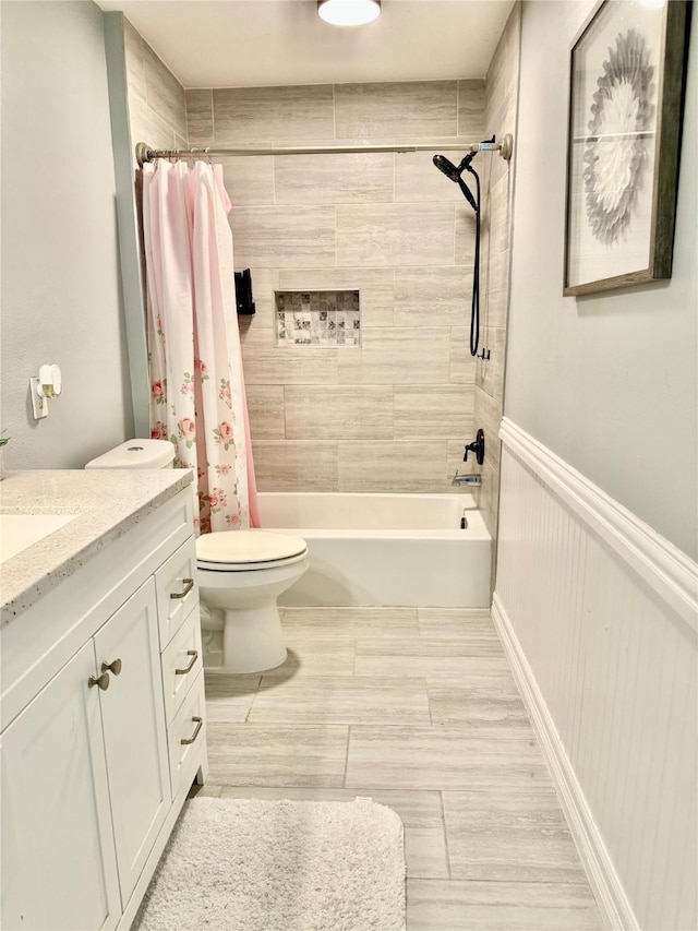 full bath featuring shower / tub combo with curtain, toilet, vanity, and wainscoting