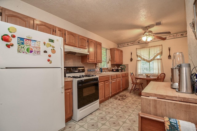 kitchen featuring visible vents, under cabinet range hood, white appliances, light floors, and ceiling fan