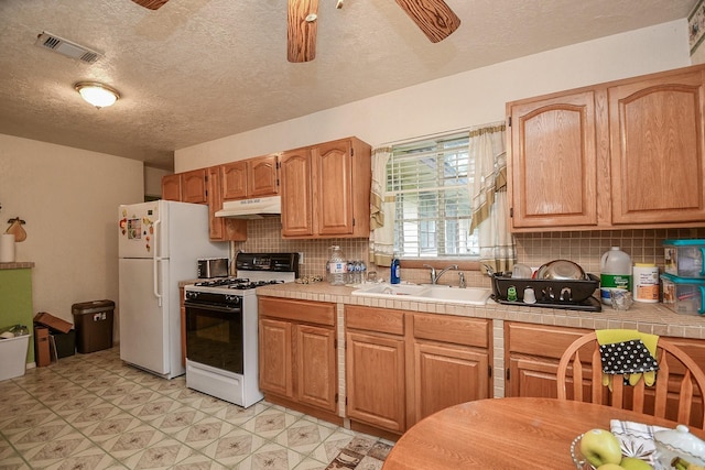 kitchen with white appliances, visible vents, ceiling fan, a sink, and under cabinet range hood