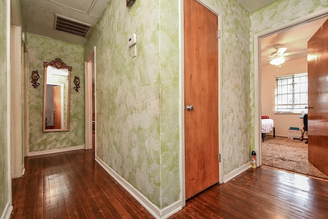 hallway with visible vents, wallpapered walls, and wood-type flooring