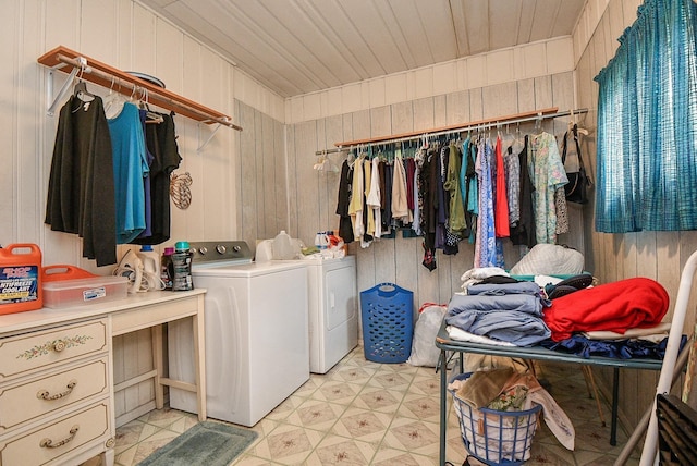 washroom featuring wooden walls, separate washer and dryer, light floors, and laundry area