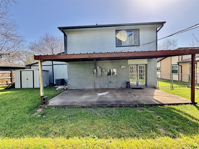 rear view of house with fence, a shed, a yard, an outbuilding, and a patio