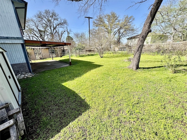 view of yard featuring an attached carport, a fenced backyard, and a patio