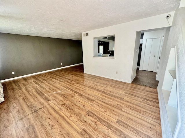 spare room featuring visible vents, baseboards, and wood finished floors