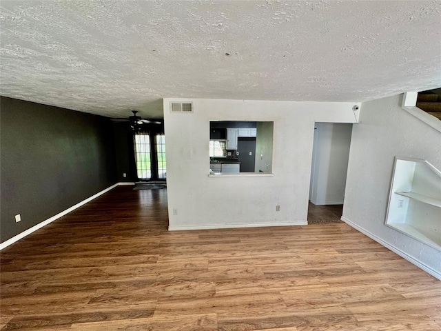 unfurnished living room with visible vents, baseboards, wood finished floors, a textured ceiling, and a ceiling fan