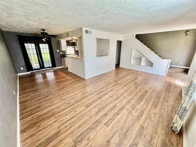 unfurnished living room featuring visible vents, a textured ceiling, a ceiling fan, and wood finished floors