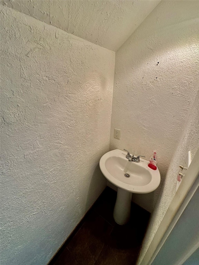 bathroom featuring a textured wall and a sink