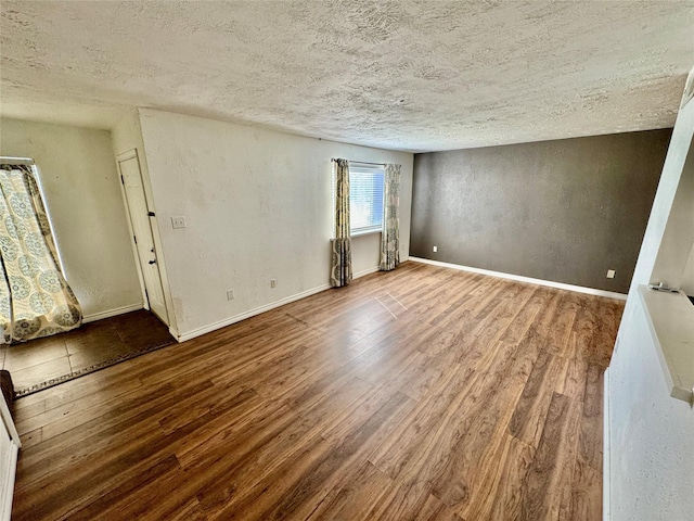 unfurnished room featuring baseboards, a textured ceiling, wood finished floors, and a textured wall