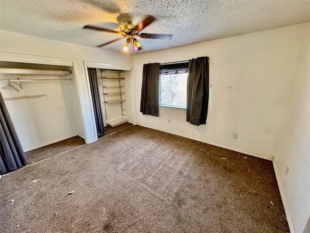 unfurnished bedroom with two closets, a ceiling fan, a textured ceiling, and carpet flooring