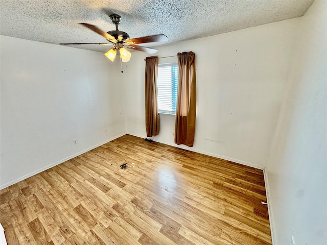 spare room with light wood finished floors, baseboards, a textured ceiling, and a ceiling fan