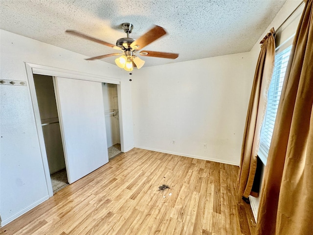 unfurnished bedroom featuring ceiling fan, light wood-type flooring, a closet, and a textured ceiling