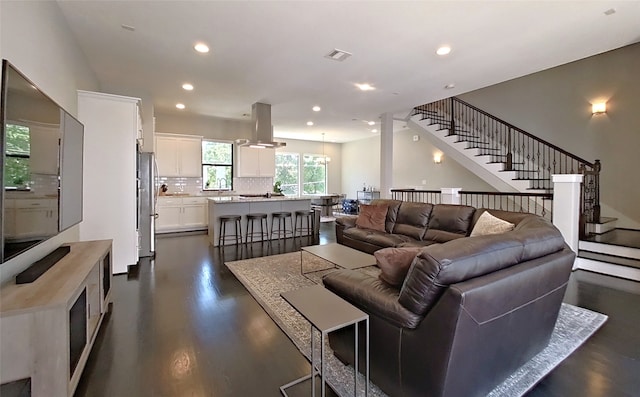 living room with dark wood-style floors, visible vents, recessed lighting, and stairs