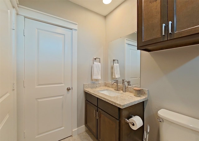 half bath with baseboards, toilet, and vanity