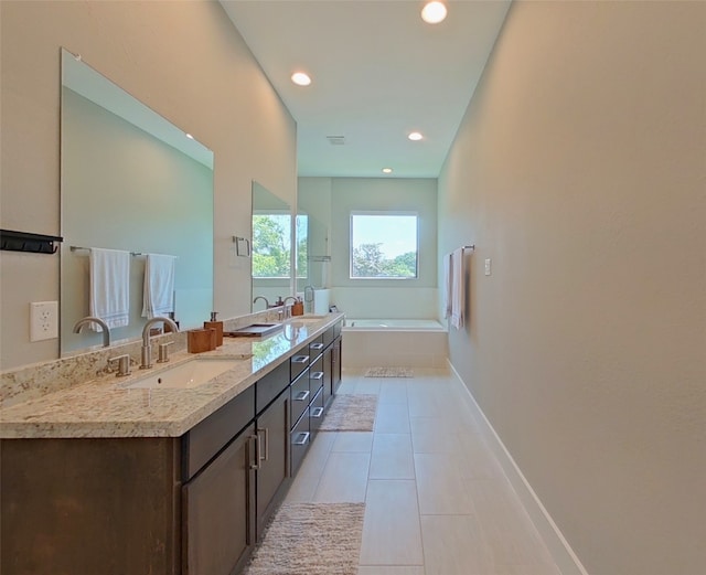 bathroom featuring tile patterned floors, double vanity, a garden tub, and a sink