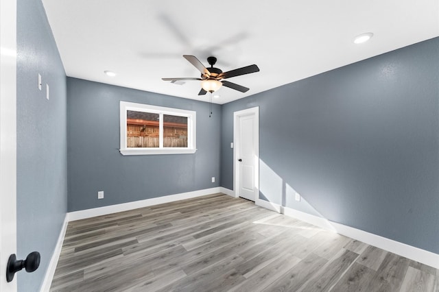 empty room with ceiling fan, baseboards, and wood finished floors