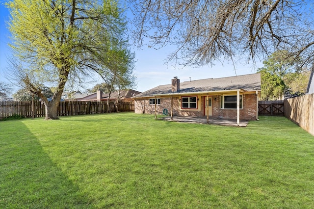 rear view of property featuring a fenced backyard, a chimney, a lawn, a patio area, and brick siding