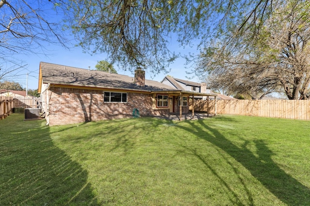 rear view of house with a fenced backyard, a yard, brick siding, central AC unit, and a chimney