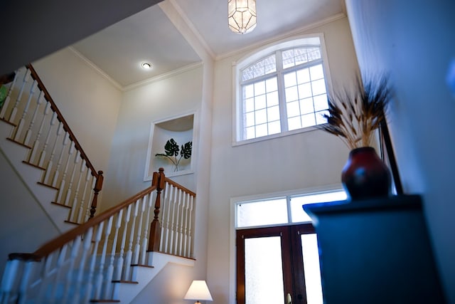 foyer with crown molding and stairway