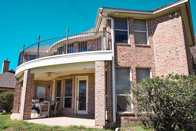 rear view of property featuring a patio, brick siding, a balcony, and a ceiling fan